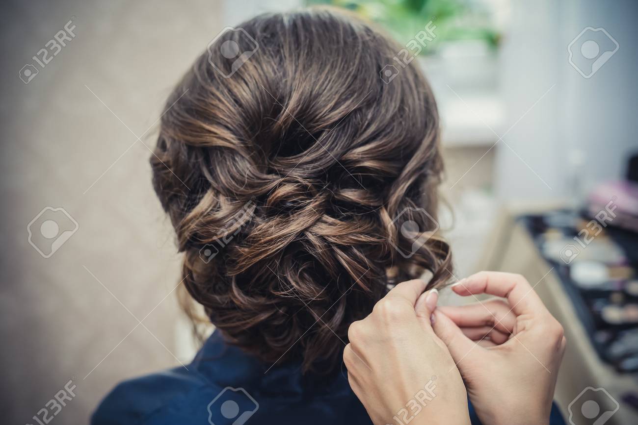 The hands of the hairdresser do wedding hairstyle