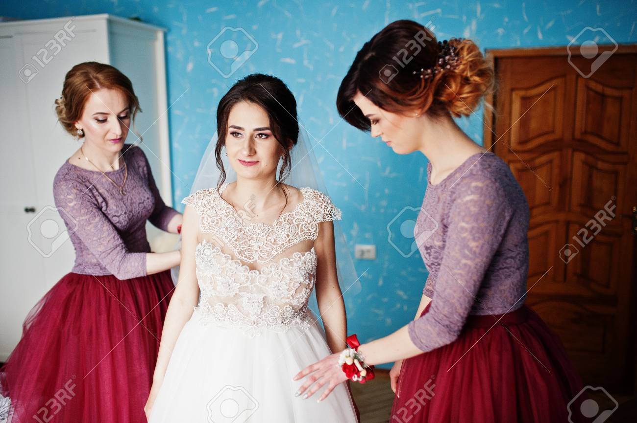 Bridesmaids helping bride to get ready for her wedding ceremony.